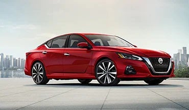 2023 Nissan Altima in red with city in background illustrating last year's 2022 model in Performance Nissan of Pompano in Pompano Beach FL